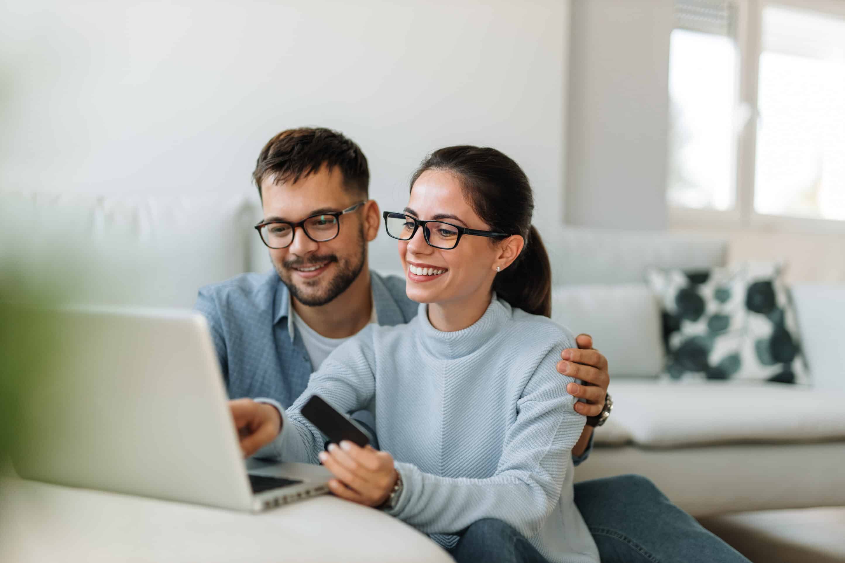 Holding credit card, both wearing glasses. Man and woman doing online shopping.